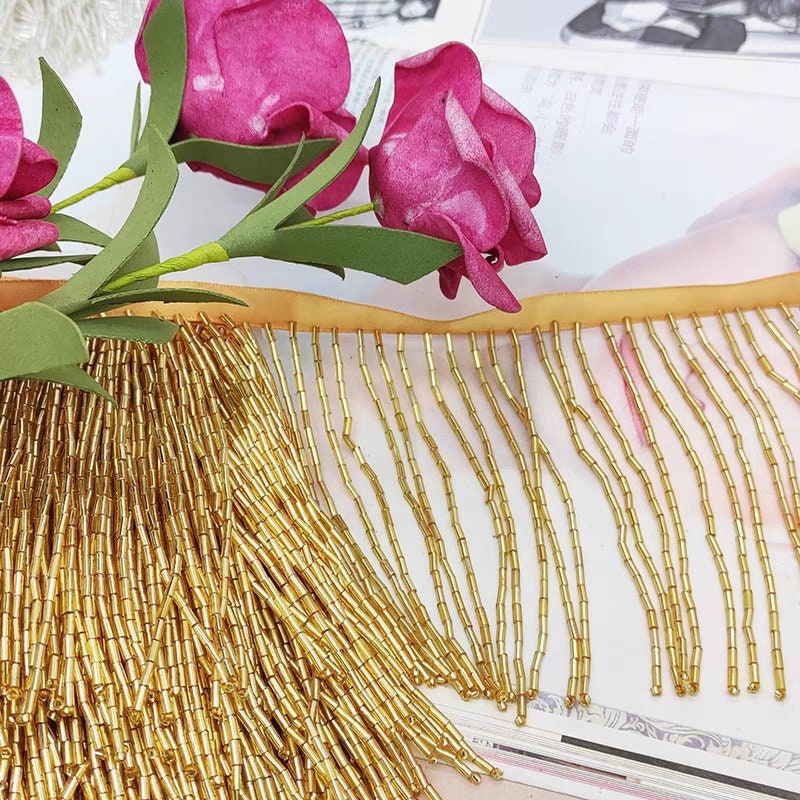 Frange perlée entièrement composée de perles tubulaires, 90 cm de long et 10 cm de large. Idéale pour la décoration de robes et costumes, ou pour abat-jour. Disponible en 10 couleurs différentes.