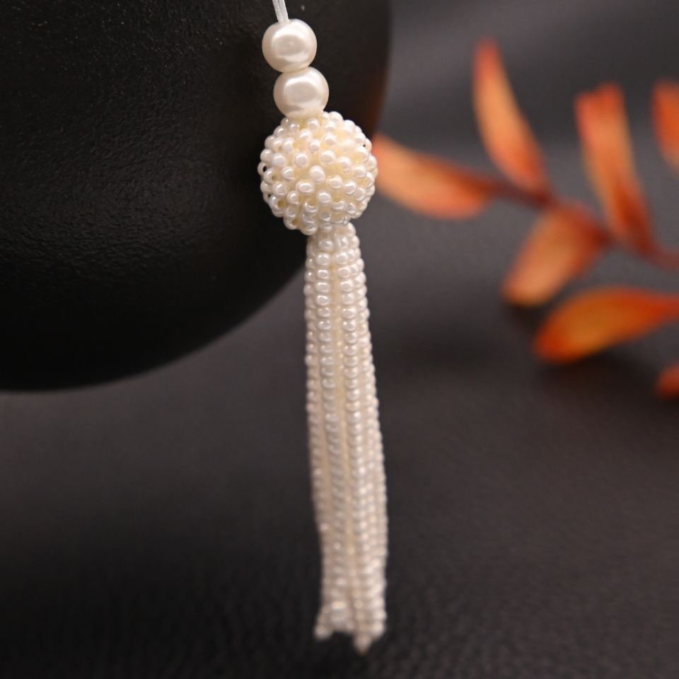 Handgemaakte 8,5 cm lange hanger met parelkralen en kwastje.