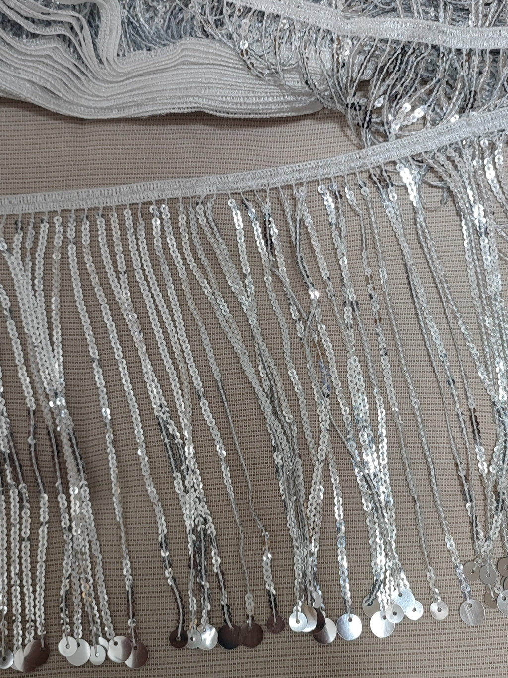 15 yards (ca. 14 meter) glinsterende, 18 cm brede, bandloze, dikke zilveren paillettenfranje, verkrijgbaar in verschillende kleuren.