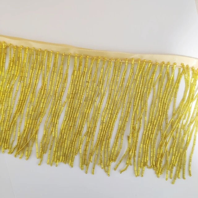 Frange perlée entièrement composée de perles tubulaires, 90 cm de long et 10 cm de large. Idéale pour la décoration de robes et costumes, ou pour abat-jour. Disponible en 10 couleurs différentes.