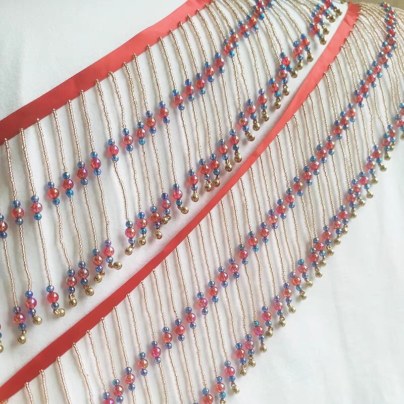 Frange perlée faite main, 90 cm de long x 10 cm de large, composée de perles rouges brillantes et de clochettes. Idéale pour abat-jour ou à réaliser soi-même.