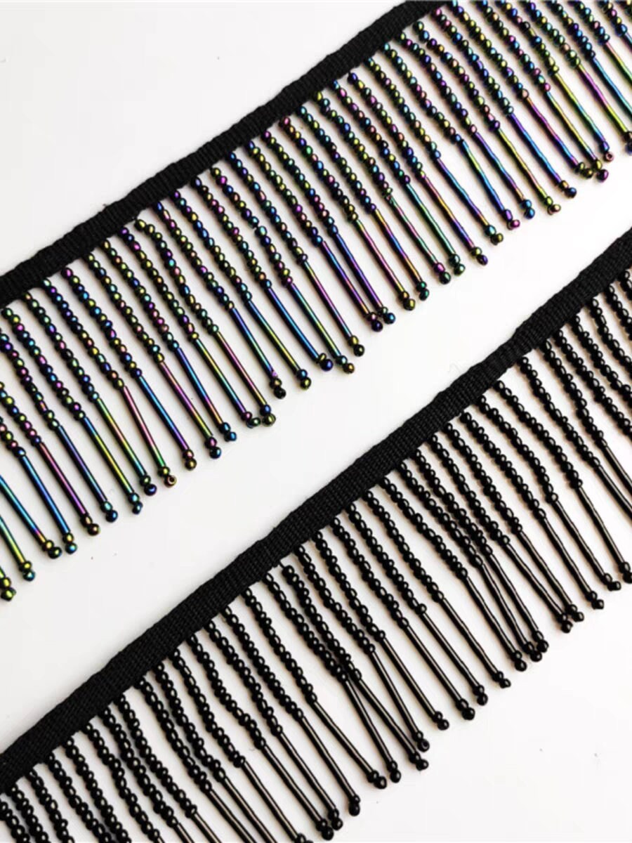 Handgemaakte kralenfranje van 90 cm lang en 6 cm breed, gemaakt van irisblauwe zaadkralen en lange buiskralen. Geschikt als lampenkapfranje, jurkfranje of voor het zelf naaien van kralen.