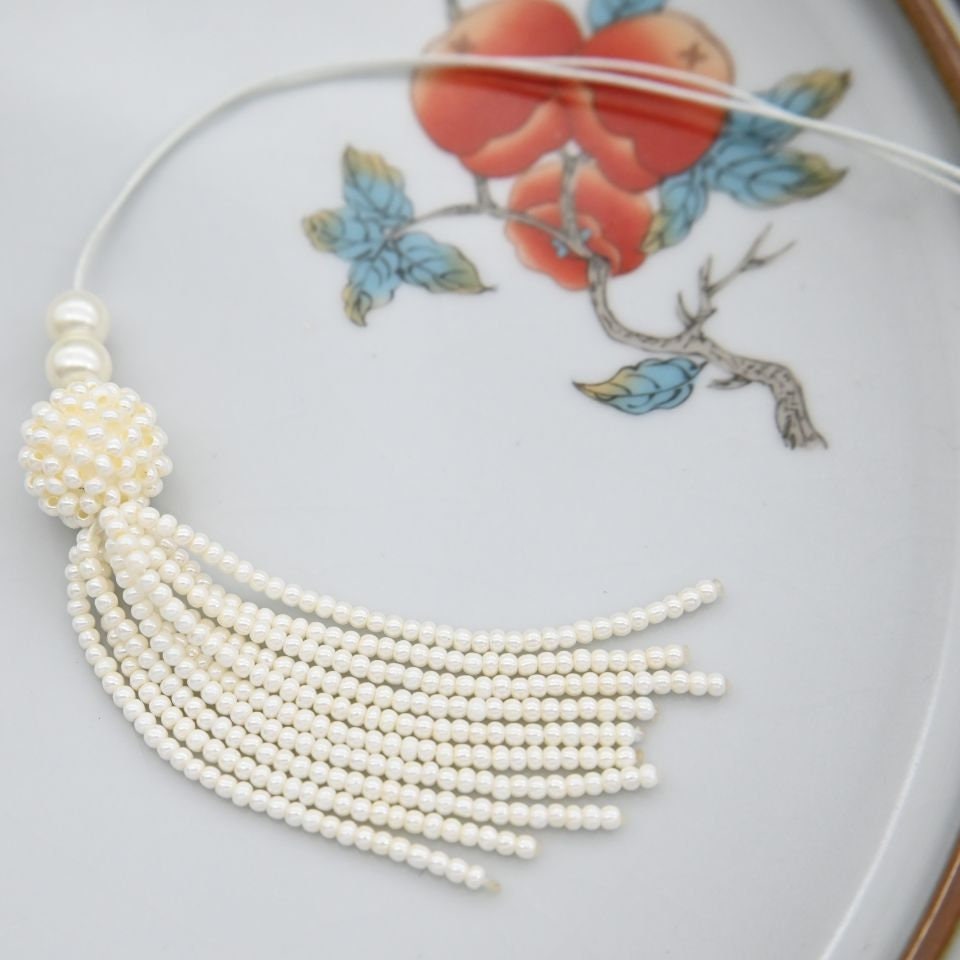 Handgemaakte 8,5 cm lange hanger met parelkralen en kwastje.