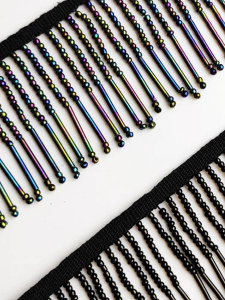 Handgemaakte kralenfranje van 90 cm lang en 6 cm breed, gemaakt van irisblauwe zaadkralen en lange buiskralen. Geschikt als lampenkapfranje, jurkfranje of voor het zelf naaien van kralen.