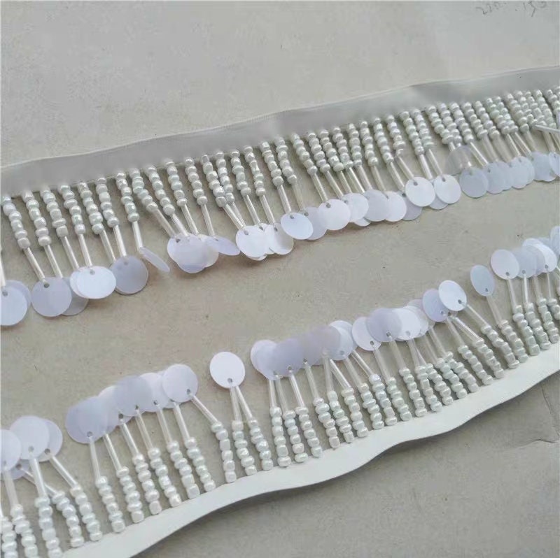 Handgemaakte kralenfranje van 90 cm lang en 3 cm breed, met zaadkralen en pailletten, in zwart, wit en beige.