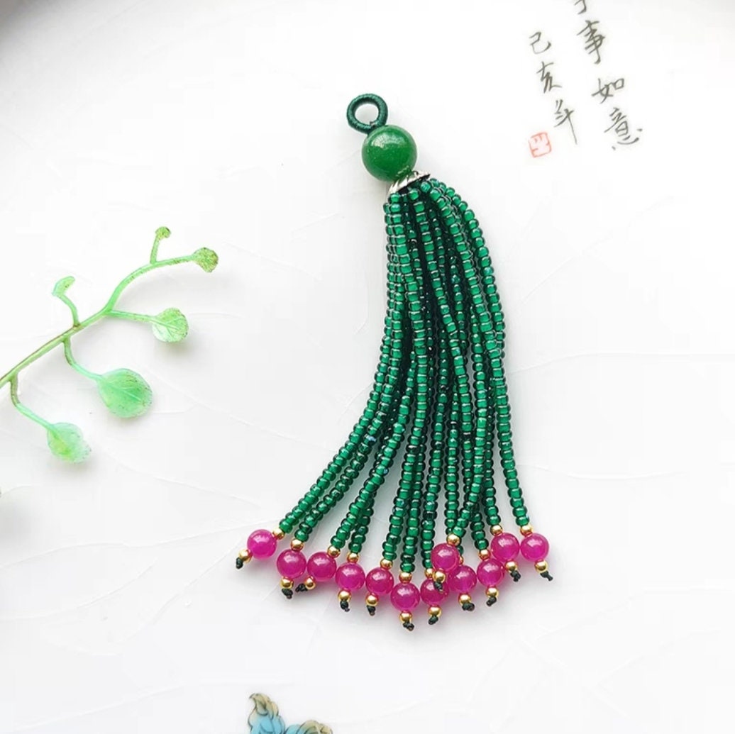 Handgemaakte hanger met parels en edelstenen, 8-9 cm lang, versierd met een franje en kwastje.