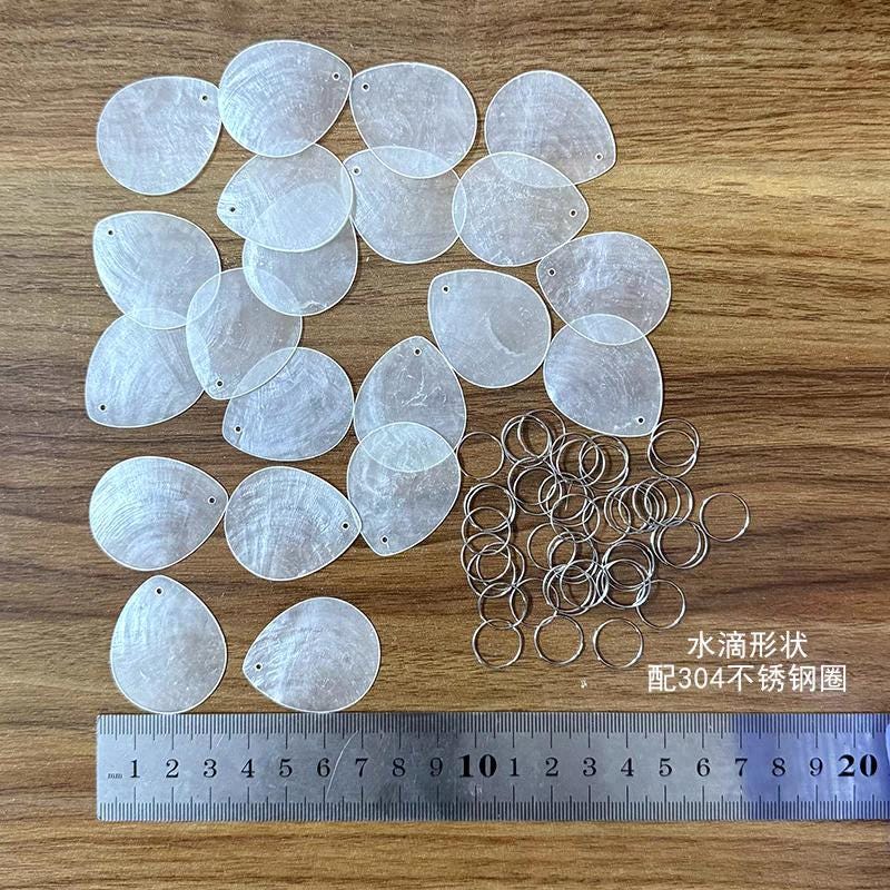 50 disques de nacre naturelle, transparents, en forme d'arbre, de papillon, de cœur, de larme et de fleur.