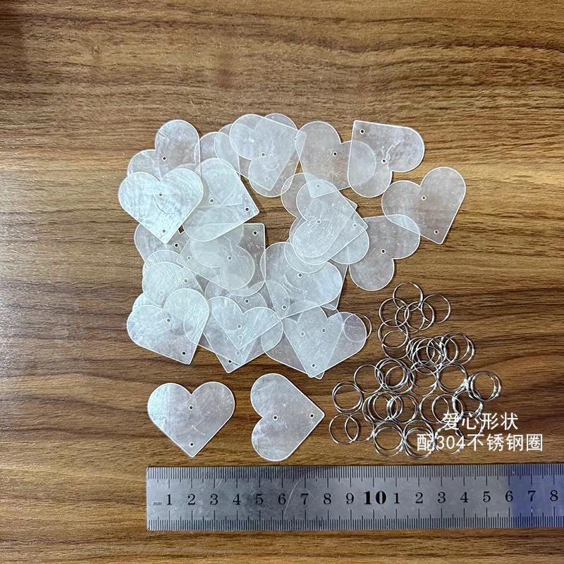 50 disques de nacre naturelle, transparents, en forme d'arbre, de papillon, de cœur, de larme et de fleur.