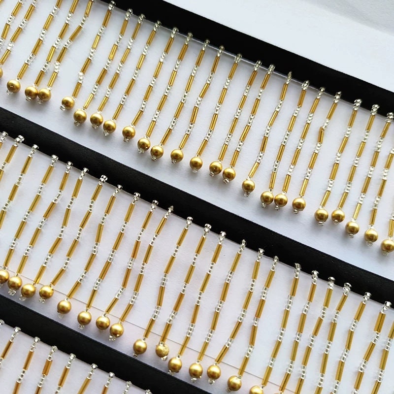 Handgemaakte lampenkapfranje van 90 cm lang en 5 cm breed met gouden kralen.