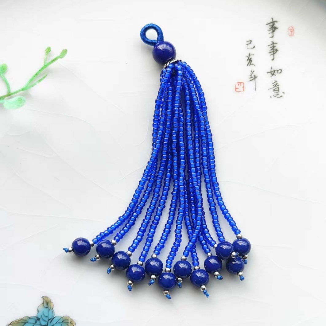 Handgemaakte hanger met parels en edelstenen, 8-9 cm lang, versierd met een franje en kwastje.