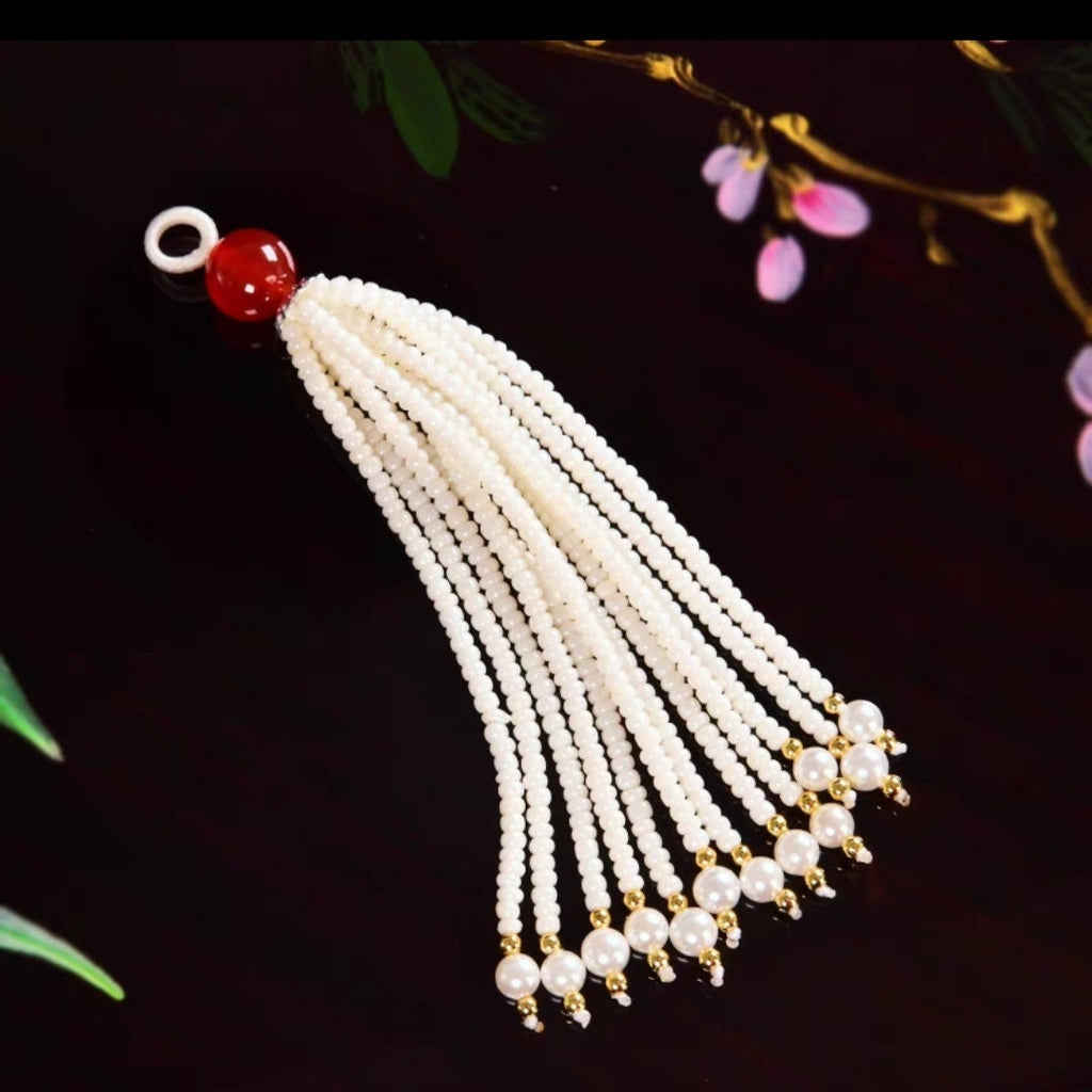 Perles artisanales de 8 à 9 cm de long, ornées de perles et de pierres précieuses émaillées, avec franges et pompons.